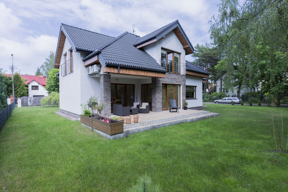 Detached modern house exterior with terrace surrounded trimmed green lawn